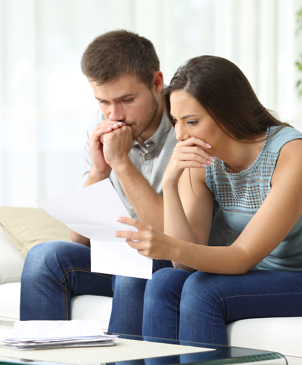 Insurance Couple on couch reading piece of mail