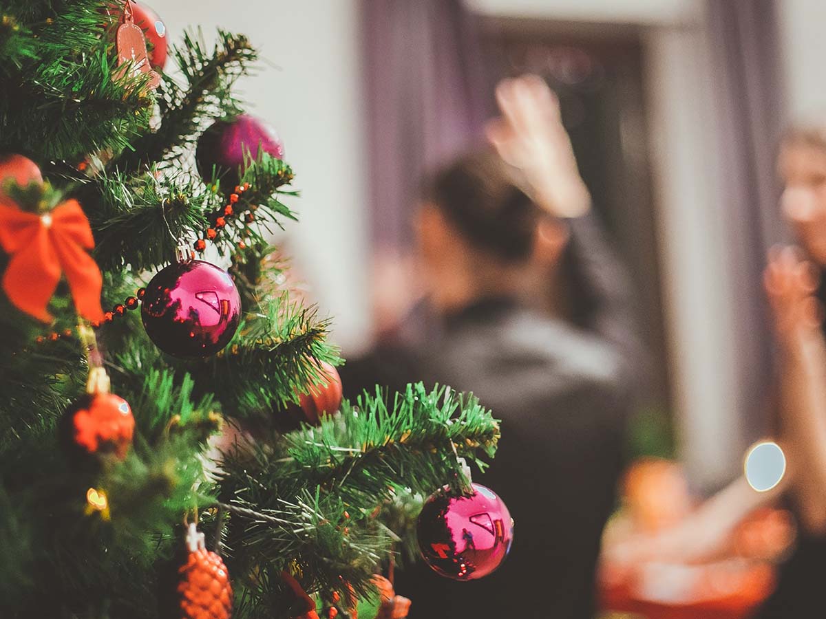 image of christmas tree in focus with people dancing in the background.