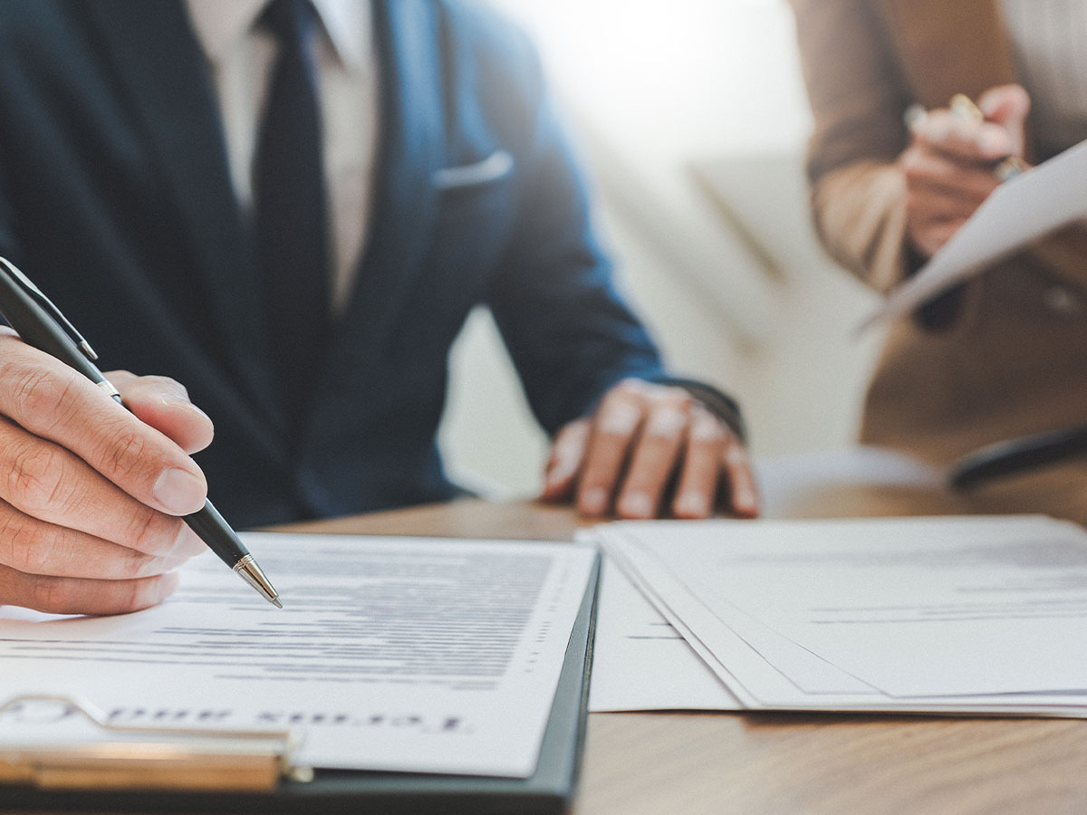 Man in suit points at paperwork with a pen