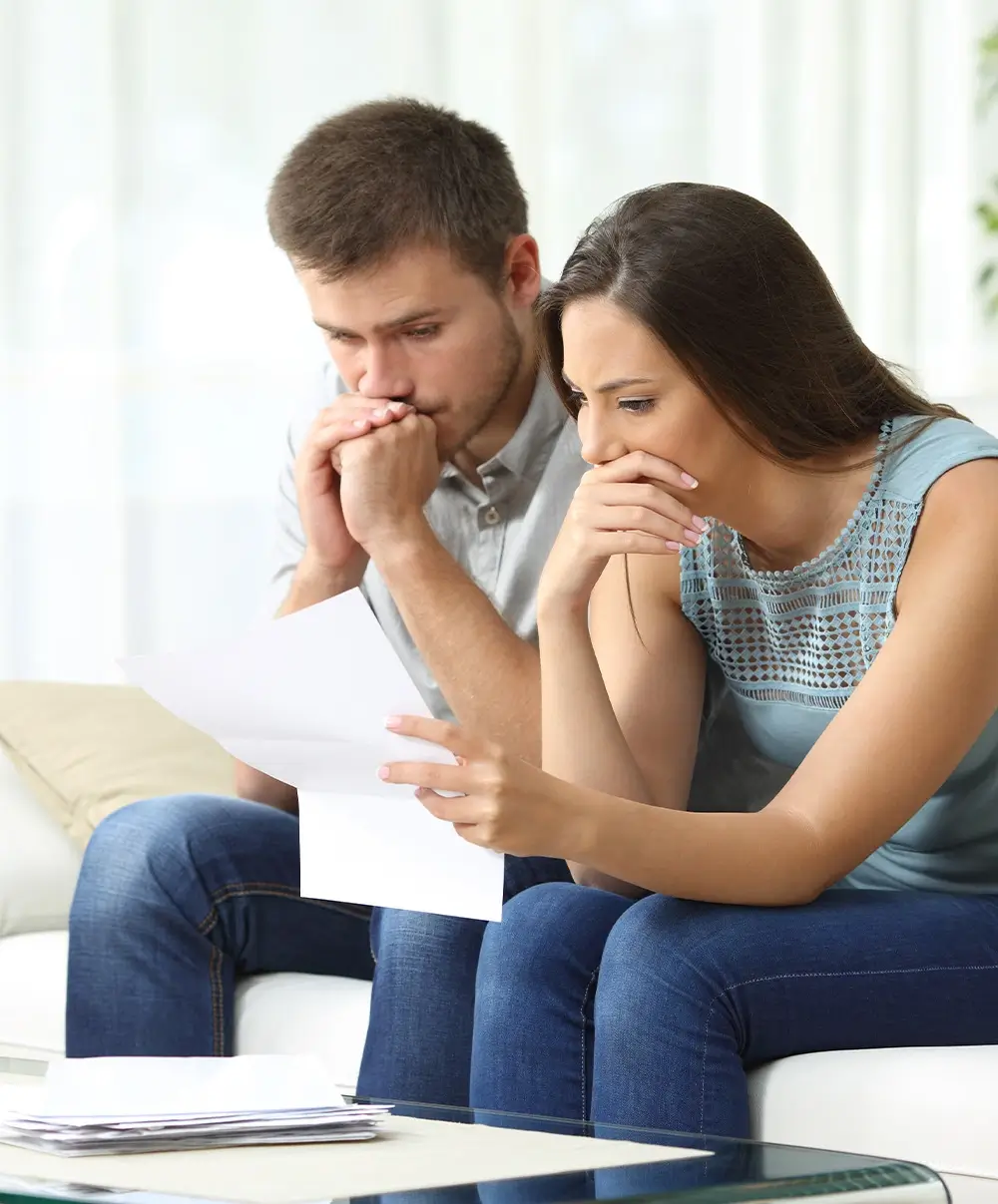 Couple on couch reading piece of mail